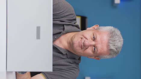 Vertical-video-of-Home-office-worker-man-looking-smugly-at-camera.